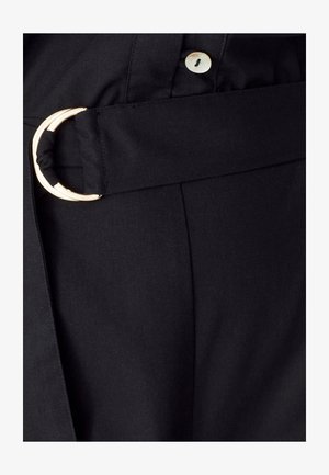 Mustat kankaiset vyöt, joissa on kultasävyinen pyöreä solki, joka tuo esiin sileän tekstuurin ja siistin, jämäkän siluetin.