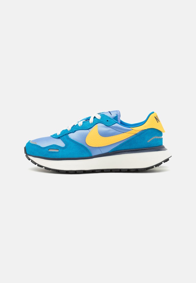 Nike sneakers with a blue and yellow color scheme, featuring a mix of suede and mesh materials, white laces, and a thick black outsole.