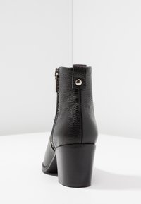 Stivale alla caviglia nero realizzato in pelle testurizzata, con zip posteriore e tacco spesso, dalla finitura liscia e con dettagli metallici.