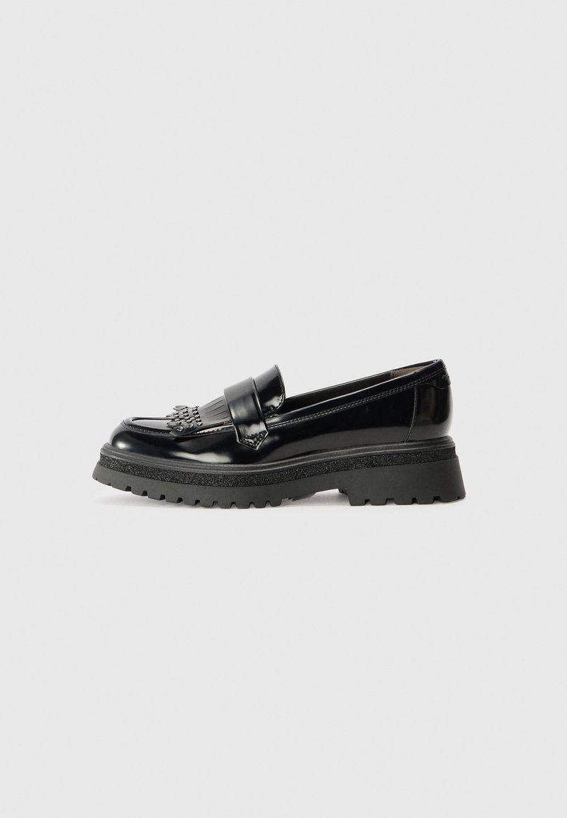 Mocassin en cuir noir brillant avec semelle épaisse à crans et détail à franges sur le dessus, vu de côté sur fond clair uni.