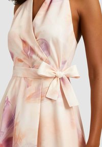 Abito con stampa floreale in colori pastello chiari, caratterizzato da un design avvolgente, tessuto morbido e dettaglio di cintura annodata in vita.