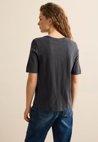 Mørkegrå bomulds t-shirt med korte ærmer og rund hals, med en glat tekstur og en afslappet pasform, parret med blå jeans.