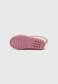 Suola di sneaker in gomma rosa con superficie testurizzata, caratterizzata da motivi geometrici e punta arrotondata, progettata per trazione e durata.