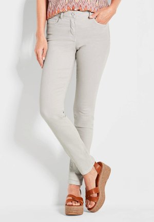 Pantalon ajusté gris clair en tissu doux, accompagné de sandales à plateforme marron avec des lanières croisées et des semelles tissées texturées.