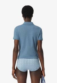 Paitapusero vaaleansinisestä kankaasta, jossa on lyhyet hihat, yhdistettynä vaaleansiniset palmikkoneulehousut, joissa on resorivyötärö.