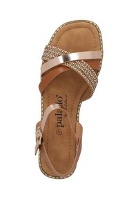 Tan Sandalen mit gekreuzten Riemen aus glatten und strukturierten Materialien, mit metallischen Akzenten und einem gepolsterten Fußbett.