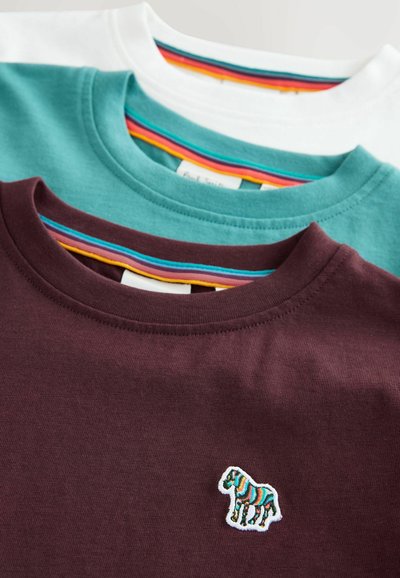 Trīs T-krekli sakrauti: bordo, zili zaļš un balts. Katram ir apaļa apkakle un tiem ir daudzkrāsains svītrains iekšējais apkakles elements un zebra logotips.