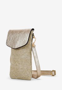 Bolso metálico dorado con un cuerpo tejido texturizado y una solapa brillante. Presenta una correa desmontable y acentos de hardware en tono dorado.
