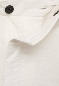 Tessuto bianco con una texture liscia, dotato di un bottone nero e una zip. Orlo e cuciture sono rifiniti in modo ordinato.