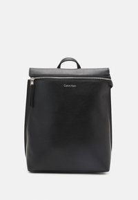 Czarny skórzany plecak o teksturowanym wykończeniu, z zamkiem błyskawicznym i uchwytem u góry. Posiada detal z logo z przodu oraz minimalistyczny design.