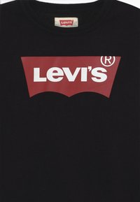 Černá mikina s kulatým výstřihem, na které je velké červené logo Levi's® s bílým nápisem, vyrobená z měkké tkaniny, s žebrovaným detailem kolem výstřihu.