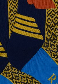 Kniestrümpfe mit navy-blauem Grund, gelben Streifen und geometrischen Mustern, orangefarbenen Akzenten und einem blauen Bund mit Logodetail.