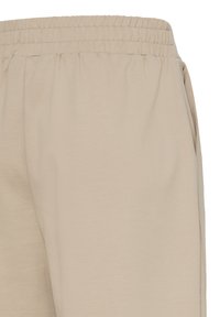Pantalon de survêtement beige avec une taille élastique, offrant une texture lisse, une coupe décontractée et des poches latérales pour plus de fonctionnalité.