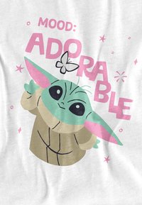 Cartoonfigur mit grüner Haut und großen schwarzen Augen, die einen braunen Umhang trägt. Text: "Stimmung: Niedlich". Schmetterlinge und Sterne ergänzen das Design.