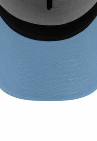 Blaues Cap mit strukturiertem Stoff, schwarzem Schirm und grauem Innenfutter. Gebogener Schirm mit genähten Details und einem zentralen Belüftungsloch.