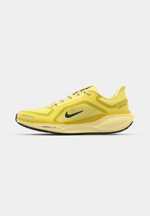 Basket de course Nike jaune avec tige en mesh, accents texturés, semelle rembourrée et logo sombre. Équipée d'un système de lacets et d'un talon renforcé.