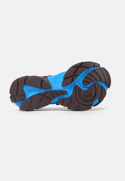 Sko sula med en övervägande svart gummibas, som har en ljusblå mellansula och texturerat mönster för bra grepp. Böjd design med distinkta mönster.