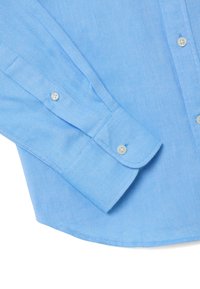 Camicia azzurro chiaro con bottoni, realizzata in tessuto strutturato, con colletto appuntito, maniche lunghe con polsini abbottonati e strisce diagonali.
