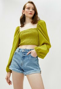 Grøn struktureret crop top med puffede ærmer, kombineret med højtaljede denimshorts med frynset kant og slidt finish.