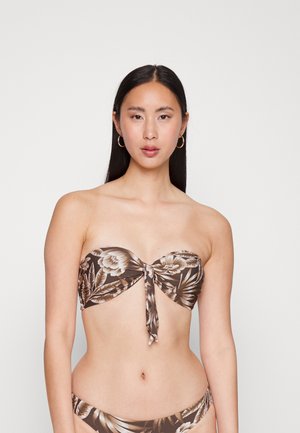 Biquíni bandeau castanho com detalhe frontal atado; o tecido apresenta grandes flores creme e folhas verdes sobre um fundo escuro.