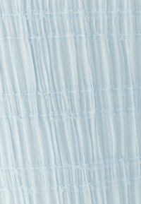 Svetlo modra tkanina z mehko, prosojno teksturo, s horizontalnimi volančki in kontrastnim čipkastim trakom.