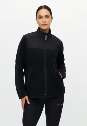 Black zip-up jacket with a mix of smooth and textured materials, featuring side pockets and a high collar. Plain design without patterns.