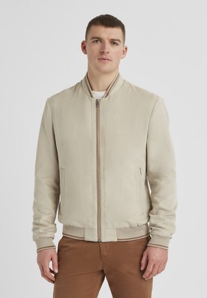 Beige Bomberjacke mit glatter Oberfläche, Reißverschluss, gerippten Bündchen und Saum sowie seitlichen Taschen. In einem leichten Design gestaltet.