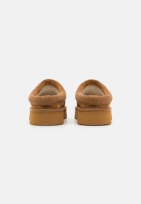 Barna nubuk bőr slip-on cipők párnázott belső résszel és lapos gumitalppal, sima, lekerekített élekkel és minimalista dizájnnal.