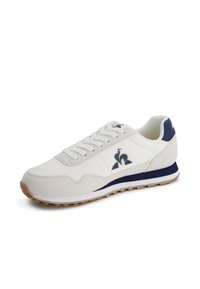 Scarpa atletica bianca e blu navy con parte superiore in suede e sintetico, chiusura con lacci, colletto imbottito, dettagli con logo e suola in gomma con trazione.