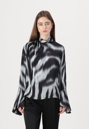 Blomst med svart og sølv tie-dye mønster, høyt halskutt, bredde-ermer, glatt satengstoff og avslappet passform. Kombinert med svarte bukser.