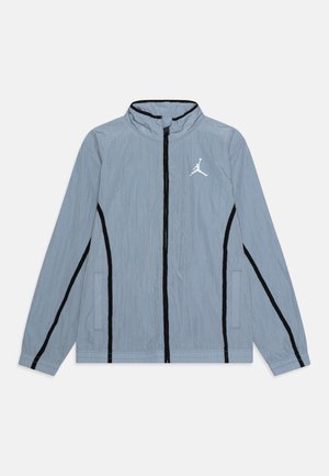 Jasnoskaźona niebieska kurtka na zamek z czarnymi pionowymi paskami, stojącym kołnierzem, bocznymi kieszeniami i białym logo Jumpman na piersi.