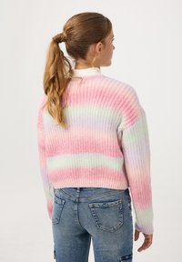 Sweter dzianinowy z pastelowymi tęczowymi paskami w odcieniach różu, zieleni i purpury; luźny krój z prążkowanymi mankietami i dołem; zestawiony z niebieskimi dżinsami.