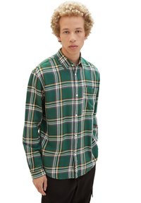 Grünes Flanellhemd mit einem Karomuster in Weiß, Gelb und Lila, mit Button-Down-Kragen, langen Ärmeln und einer Brusttasche.