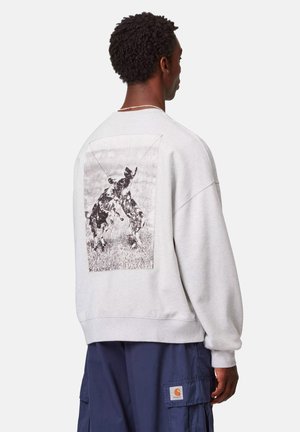 Felpa grigia con taglio morbido e polsini a coste. Presenta una grande grafica in bianco e nero di cani sulla schiena all'interno di una cornice rettangolare.