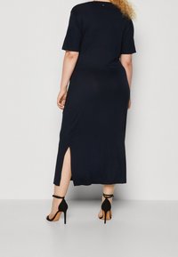 Marineblauwe, enkellange jurk met korte mouwen en zijsplitten. Zachte, gladde textuur met een ronde halslijn en minimale naadafwerking.