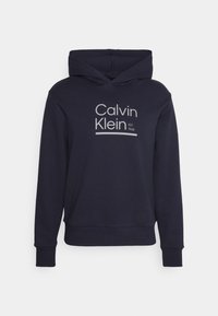 Felpa blu navy con tasca frontale a canguro, polsini e orlo ribattuti, caratterizzata da un logo grigio di Calvin Klein e testo "EST. 1968".
