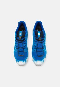 Baskets de sport bleues avec une tige texturée, des lacets et un système de fermeture à tirette, un orteil renforcé, et une semelle blanche contrastante. Design élégant avec des logos.