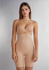 Naadloze nude bodysuit met een strapless sweetheart-halslijn en lengte tot halverwege de bovenbenen, gemaakt van soepel, elastisch materiaal zonder zichtbare naden.