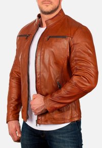 Bruine leren jas met een staande kraag, ritssluitingzakken en een getailleerd ontwerp. De textuur is glad met subtiele nerfpatronen.