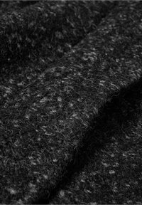 Primer plano de una tela de lana texturizada de color gris oscuro, con fibras y pliegues visibles.
