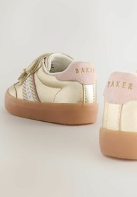 Lasten kullanväriset lenkkarit, joissa on vaaleanpunaiset mokkajalustat, tarranauhat ja ruskeat kumipohjat vaalealla taustalla.