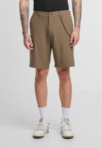 Shorts marron en tissu doux, présentant une coupe droite, deux poches avant et un détail décoratif en chaîne métallique sur la ceinture.