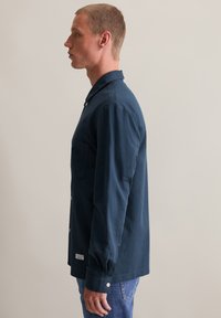 Marineblauwe button-up shirt met een puntige kraag, borstzak en lange mouwen met knoopmanchetten. Katoenen stof met een gladde textuur.