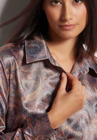 Patroon shirt met paisley-ontwerpen in pastelkleuren op een metallic grijze achtergrond, met een kraag en knoopdetails.