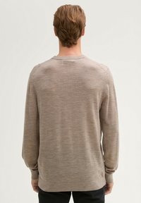 Hellbrauner langärmeliger Pullover mit Rundhalsausschnitt und gerippten Bündchen. Der Stoff wirkt weich und ist fein gestrickt, mit subtiler Textur.