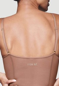 Body marrone senza cuciture con spalline sottili regolabili, dettagli in metallo dorato e una texture liscia. Nome del marchio "ITEM m6" visibile sul retro.