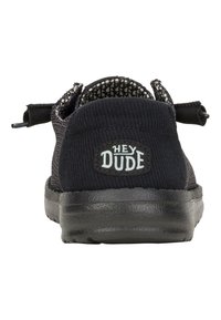 Schwarzer Stoffschuh mit strukturiertem Sohlen, elastischem Schnürdesign und einem Logo-Patch mit der Aufschrift "HEY DUDE" an der Ferse.