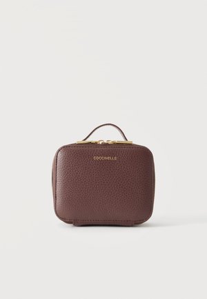 Petite trousse à maquillage en cuir marron avec fermeture éclair et poignée dorées, embossée du nom de la marque Coccinelle au centre devant.