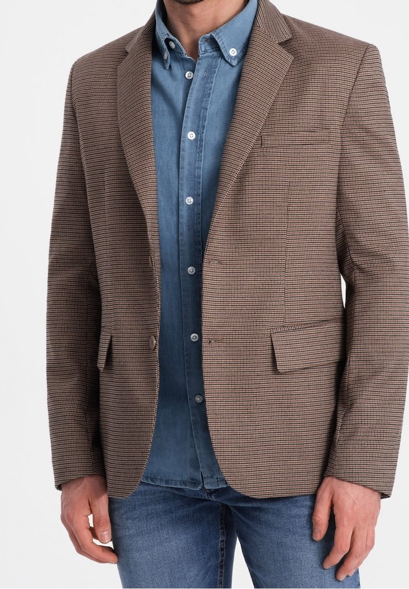 Brązowa marynarka w kratę z klapami z wycięciem, pojedynczą kieszenią na piersi i dwoma przednimi kieszeniami, nałożona na niebieską koszulę dżinsową. Gładka faktura tkaniny.