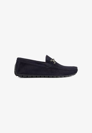 Mocassin pour homme en daim bleu marine avec semelle en caoutchouc noir et détail mors en argent sur le dessus, présenté en profil latéral sur fond blanc.